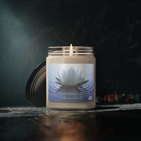 Lotus Unscented soy candle sitting on a countertop lit with the lid leaning on the side of the candle, dark bathroom shot - wellness by heart